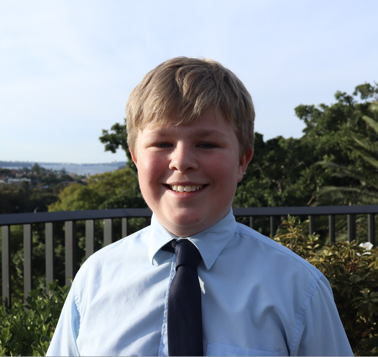 Jack Okill outdoors in a blue shirt and navy tie